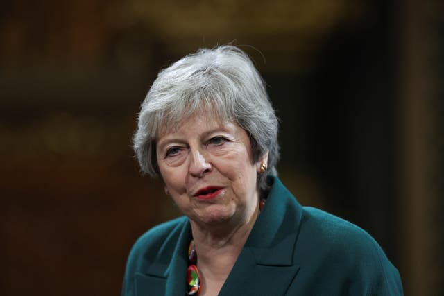 Theresa May in green jacket against dark background