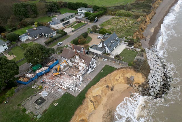 View from above of a house being demolished, which is next to eroding clifftops