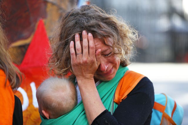 A mother cries while she holds her baby during a protest organised by Mothers Rise Up at Downing Street 