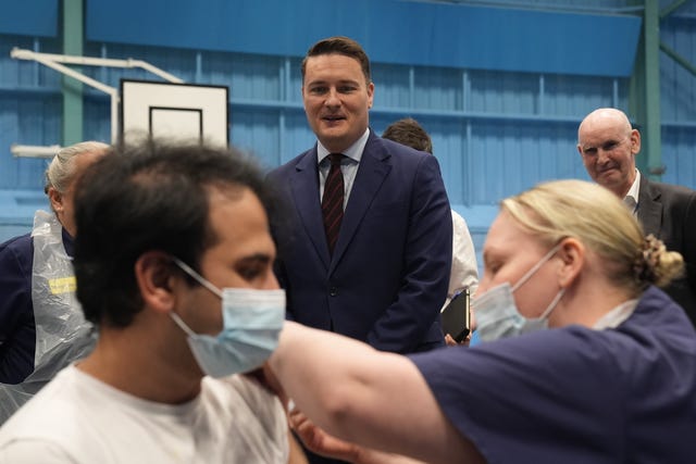 Wes Streeting watches on while a student receives a vaccine