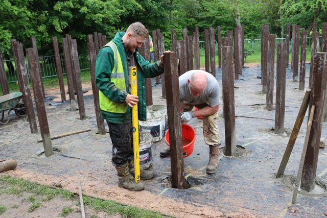 Workers refurbish the memorial tribute's wooden posts at the National Memorial Arboretum in Staffordshire