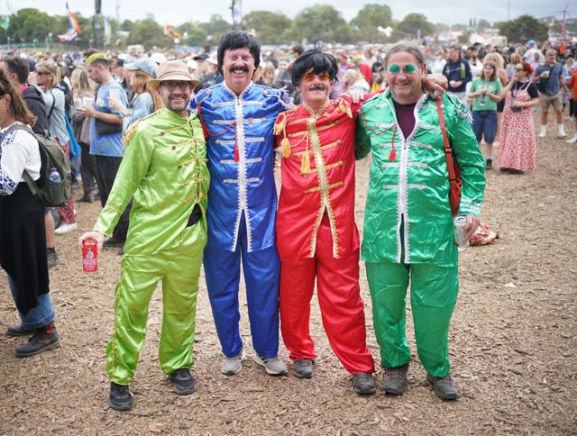 Four men dressed as the Beatles, including colourful customs, facial hair and glasses