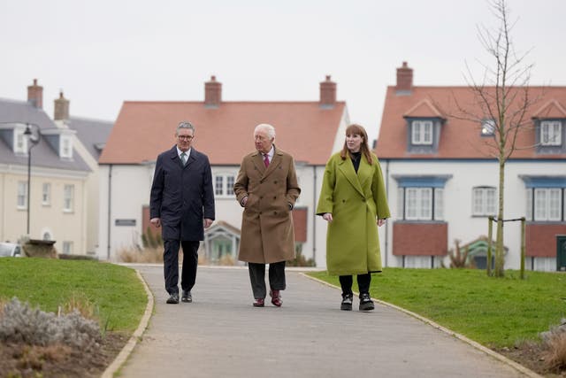 The trio stroll along a path side by side on their way to the Kew An Lergh development 