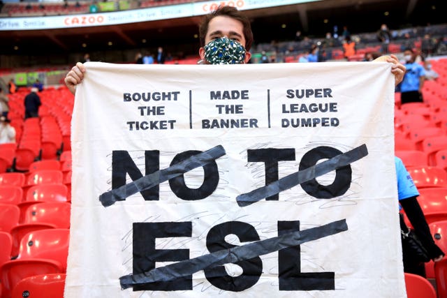 A fan holds up a banner protesting against the European Super League 