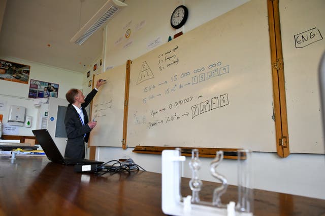 A teacher writes onto a whiteboard