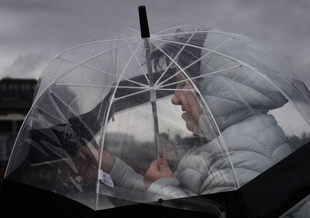 A person takes shelter under an umbrella