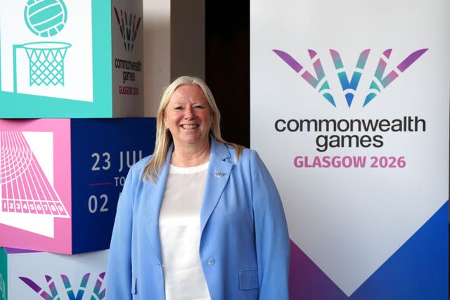 Katie Sadleir standing in front of promotional material for the Glasgow 2026 Commonwealth Games