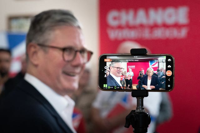 A mobile phone capturing video of Sir Keir Starmer in the background