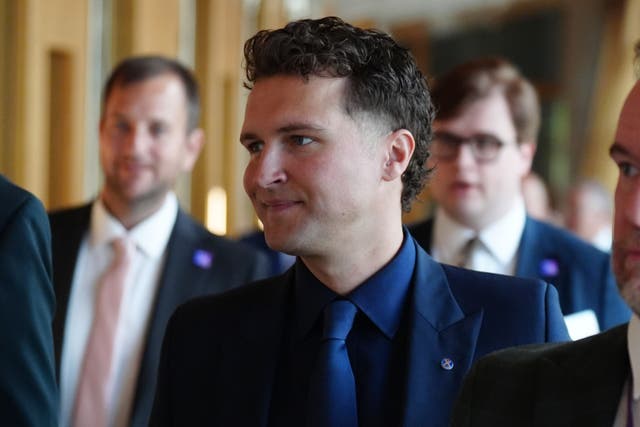 Jack Middleton smiling while walking through a corridor at Holyrood