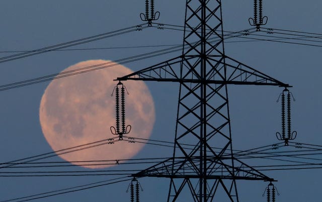 An energy pylon in front of a blue moon