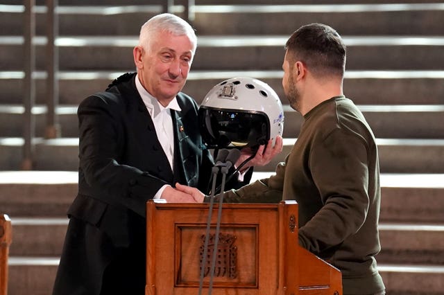 Speaker of the House of Commons Sir Lindsay holds the helmet given to him by Volodymyr Zelensky