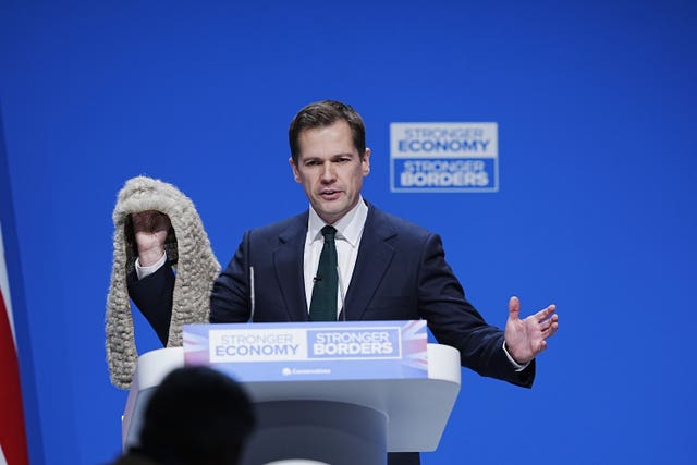 Robert Jenrick holds up a judge's wig at the 2025 Conservative Party conference