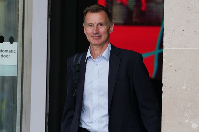 Jeremy Hunt in suit jacket and shirt, emerging from a door