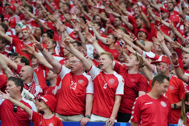 Denmark fans with their right arms raised diagonally in unison show their support during the Euro 2024 game against Germany