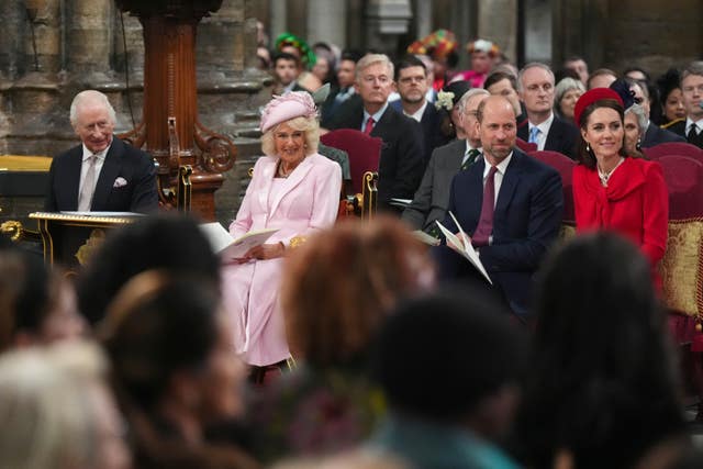The King and Queen, and the Prince and Princess of Wales smiling while seated inside Westminster Abbey