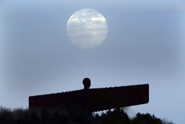 The pink supermoon is seen over the Angel of the North