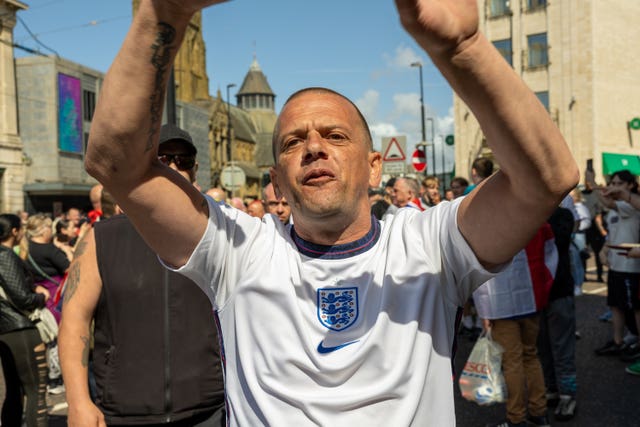 A man in a white T-shirt raises his arms