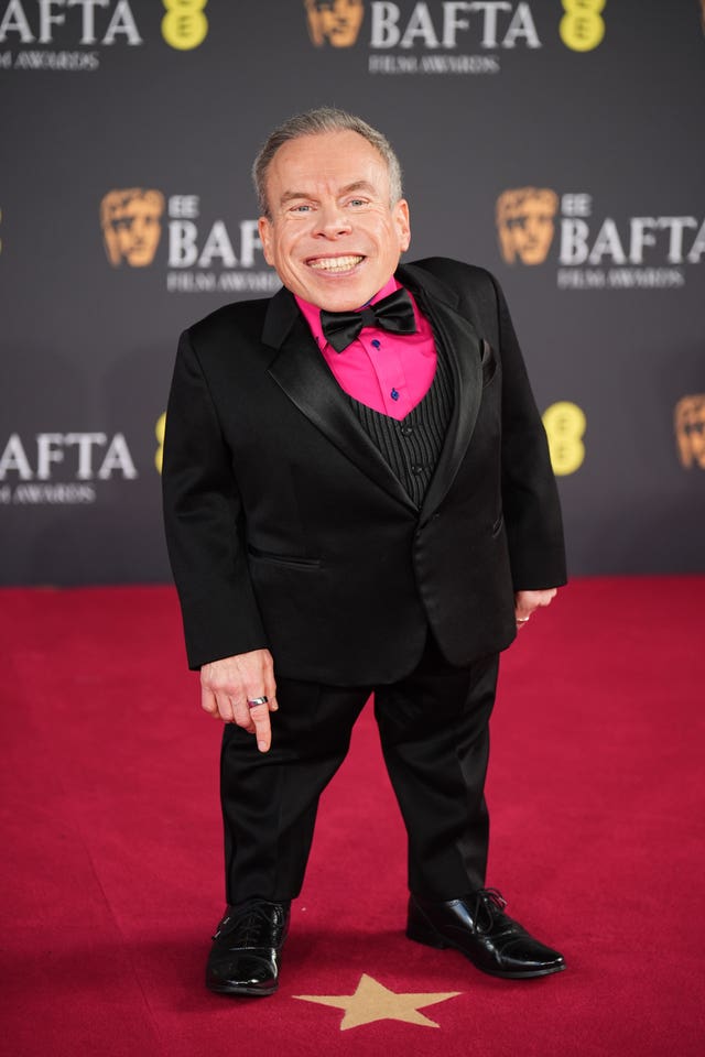 Warwick Davis chose a shocking-pink shirt under his tuxedo