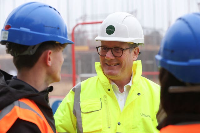 Sir Keir Starmer in high-vis and a hard hat speaks to workers on a construction site