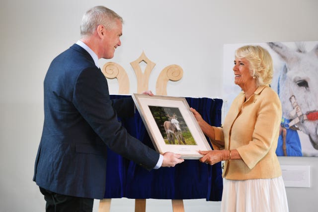 Chief executive officer of The Donkey Sanctuary Mike Baker presents the Duchess of Cornwall with a birthday gift during her visit 