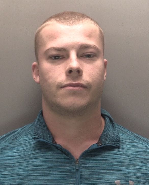 Police mugshot of a man in a blue shirt