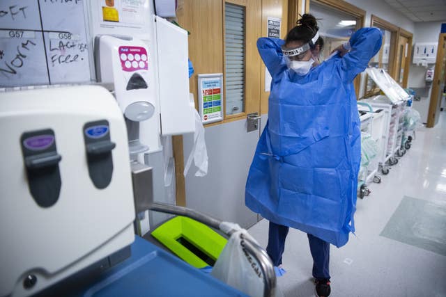 A staff nurse puts on PPE in the corridor 