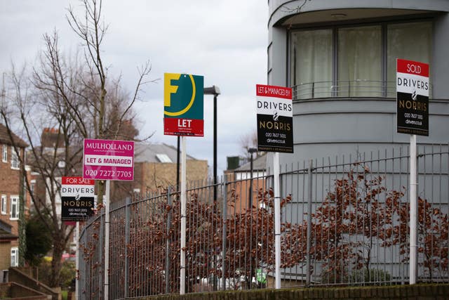 A row of Sold, Let By and For Sale estate agent signs outside houses in north London