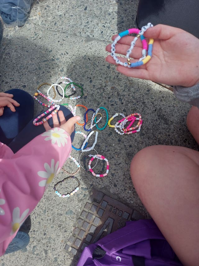The hands and arms of two young girls holding friendship bracelets