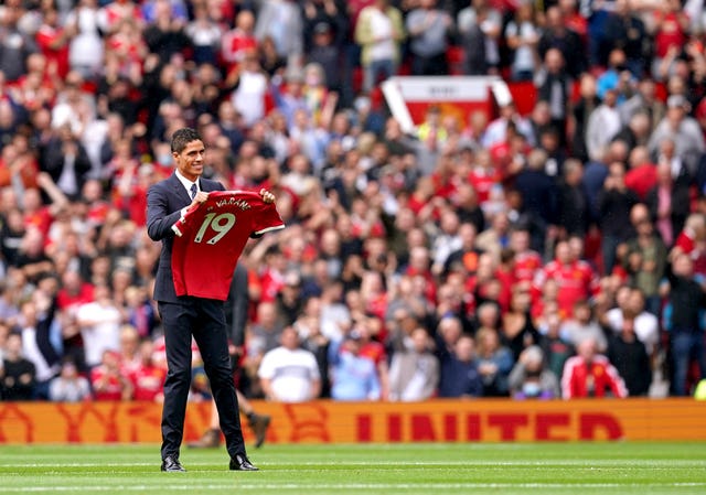 Manchester United's Raphael Varane holds up his shirt on the pitch