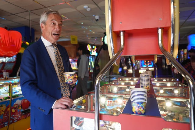 Reform UK leader Nigel Farage playing a 2p machine in Clacton-on-Sea, Essex, while on the General Election campaign trail