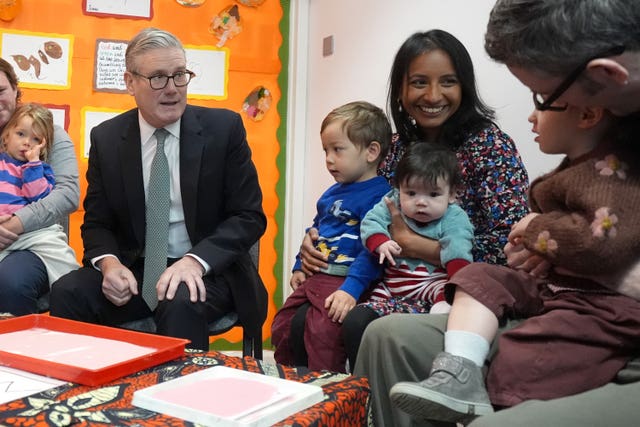Prime Minister Sir Keir Starmer, left, speaks with parents and children during a visit to a nursery 