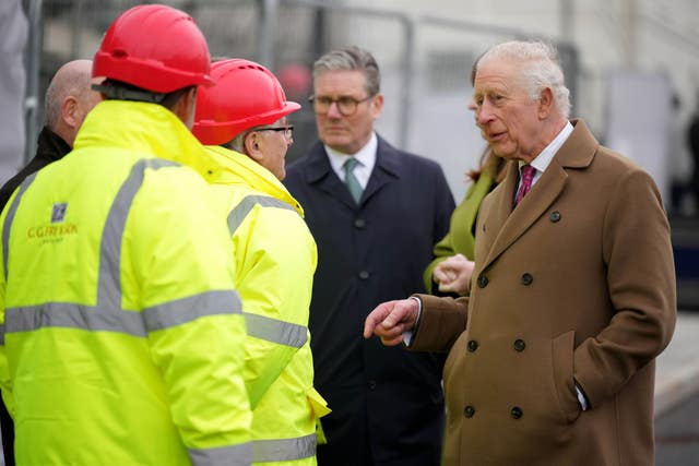 The King, accompanied by Sir Keir Starmer, chats to construction workers in hard hats and hi-vis jackets at Phase 8A, the next building phase 