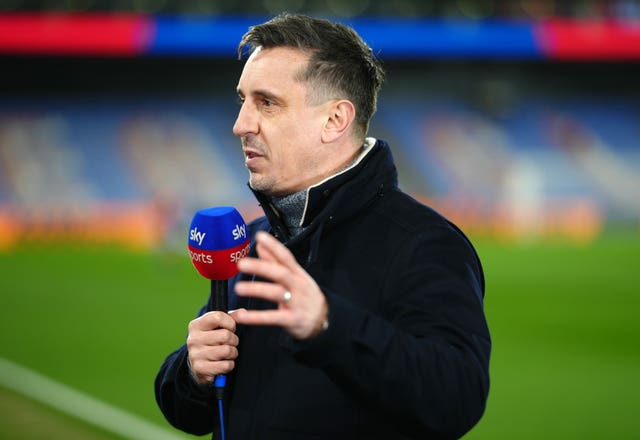 Gary Neville, holding a microphone, speaks pitchside in his role as a pundit