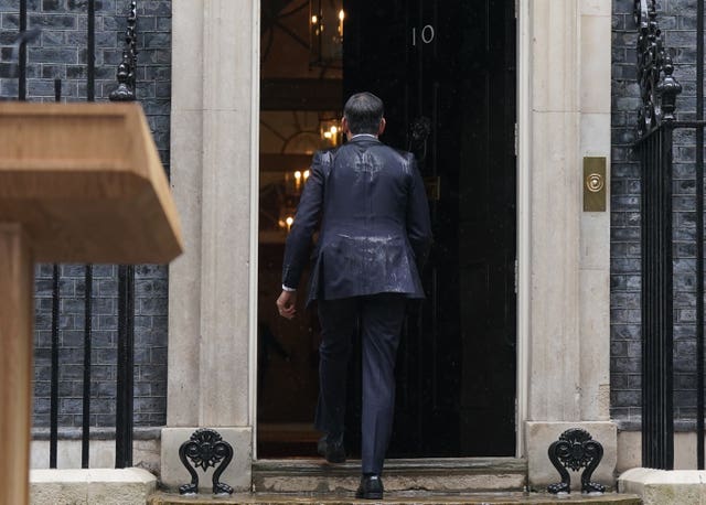 Prime Minister Rishi Sunak, soaked by rain, walks back into No 10 Downing Street