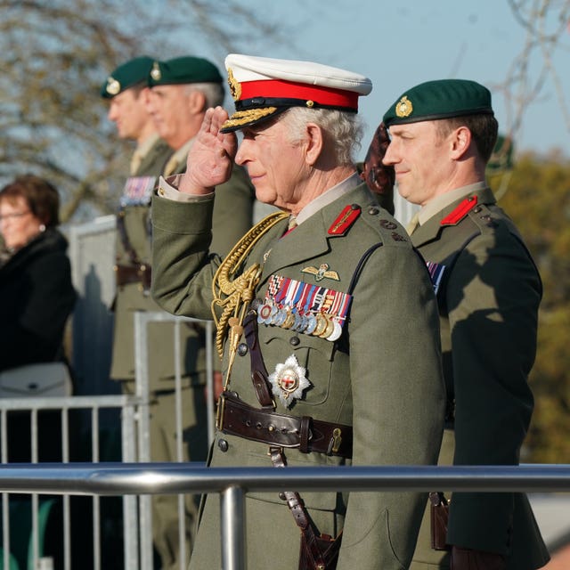 The King, wearing green uniform, saluting