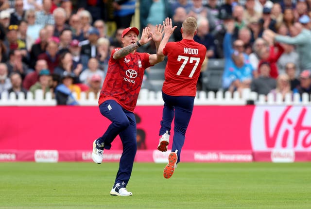 England's Luke Wood, right, leaps to high-five Brydon Carse after taking the wicket of the West Indies' Evin Lewis from the first ball of the match