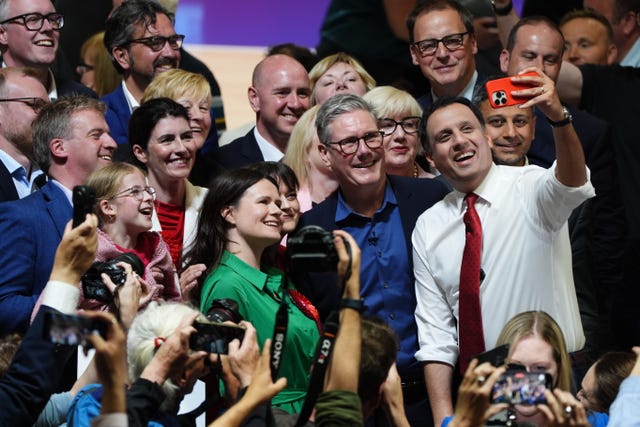 Anas Sarwar and Sir Keir Starmer taking selfies with a group of Labour supporters