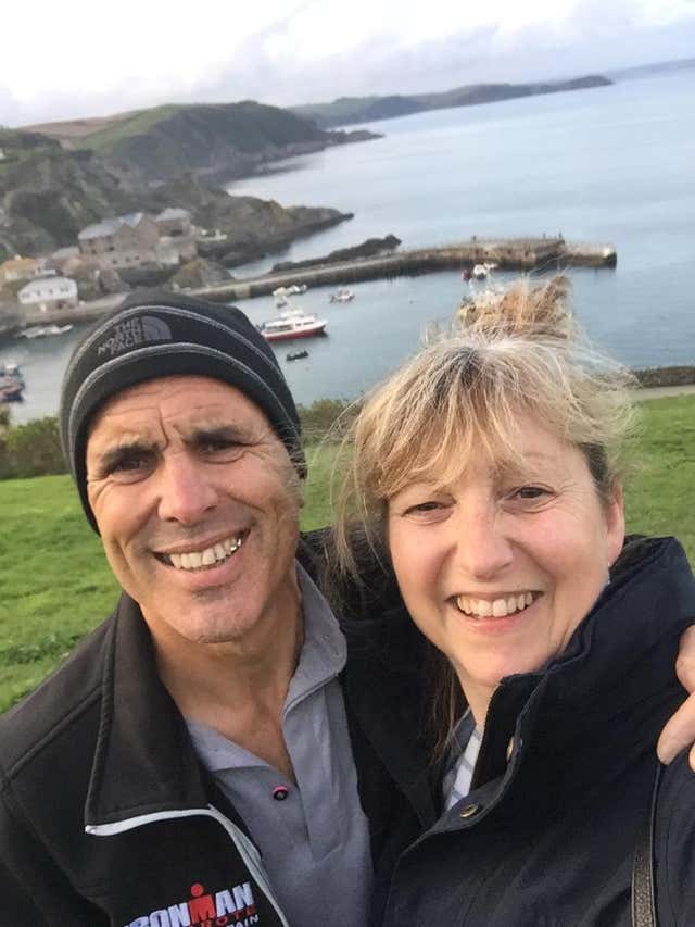 Mark Sweeney and Jayne Sweeney smile at the camera in a coastal setting