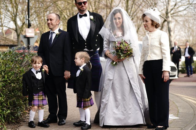 Stella Moris in street in wedding dress with family