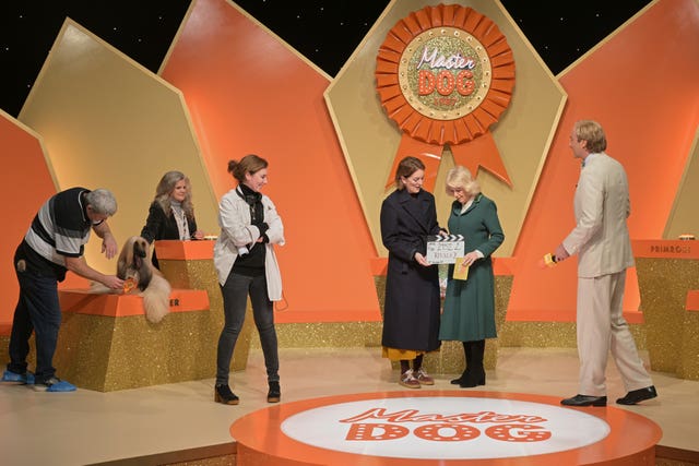 Queen Camilla holds a clapper board during a visit to the set of the series Rivals in Bristol