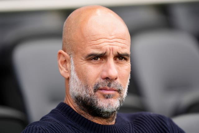 Manchester City manager Pep Guardiola sits in the dugout before a match