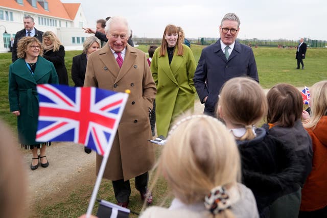 Schoolchildren wave Union flags as they greet the King accompanied by Prime Minister Sir Keir Starmer and Deputy Prime Minister Angela Rayner during a visit to Nansledan School in Newquay 