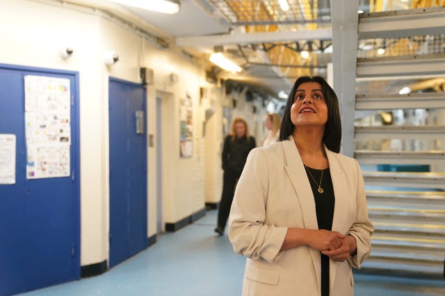 Shabana Mahmood in a prison, there's a metal staircase behind her and she's looking up at something out of frame