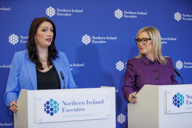 Michelle O’Neill watching on from a lectern while Emma Little-Pengelly speaks next to her