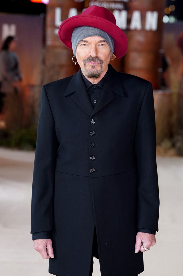 Billy Bob Thornton at a recent red carpet event, wearing a red hat on top of a grey bandana, and a black suit