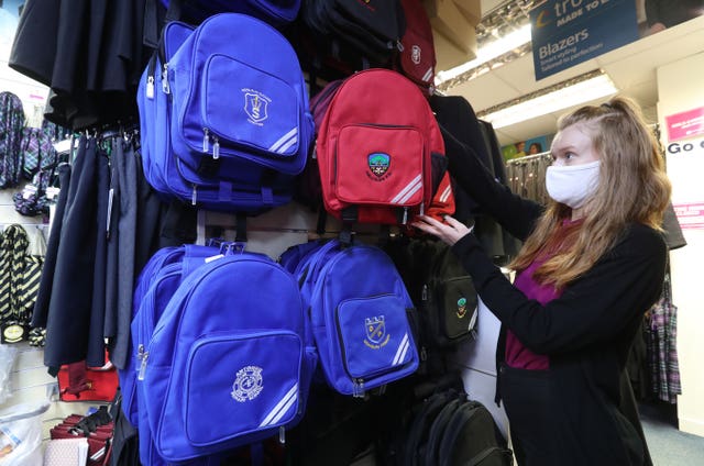 A worker hanging up school bags in a shop