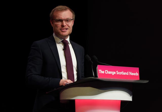 Michael Shanks speaking from a lectern which reads 'The change Scotland needs'