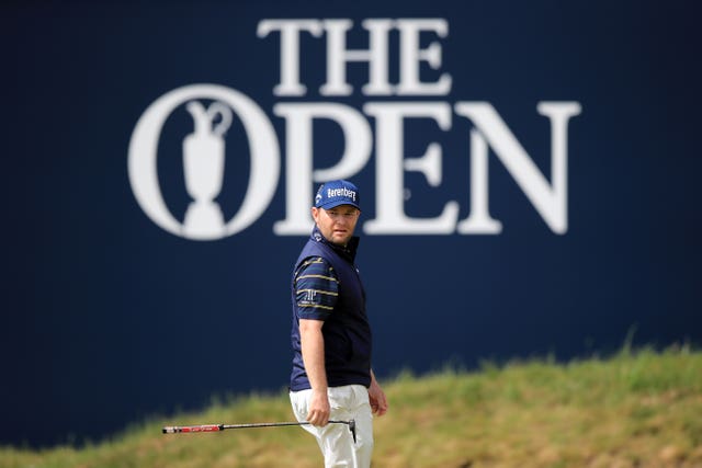 Branden Grace standing in front of The Open signage