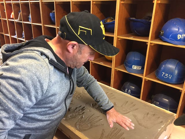 A former shipyard worker imprints his hand in wet cement