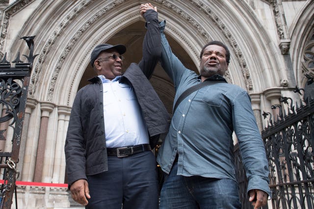 Paul Green and Cleveland Davidson raising their hands together outside court